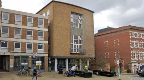 A brick building. The building has a large window on the front of it.