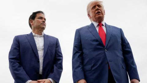 Marco Rubio in blue blazer and white shirt next to Trump in blue suit with red tie
