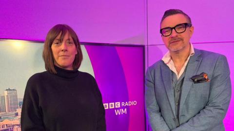 Labour MP Jess Phillips in the studio wearing a black top, hands clenched together. Presenter Ed James also in the picture, wearing a blue blazer, glasses and both looking to the camera.