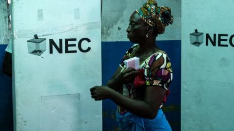 A voter finishes marking her ballot at a voting station outside Fredricks island in Monrovia on October 10, 2023