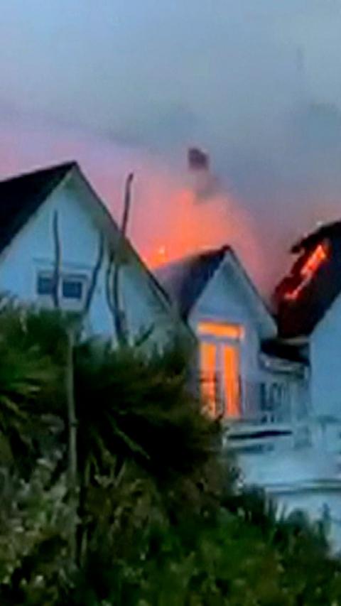 Fire and smoke comes out of white house at dusk. 