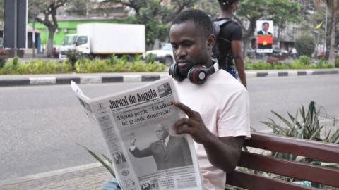 A man reads a copy of the Jornal de Angola newspaper with a headline about the death of former Angola President Jose Eduardo Dos Santos in Luanda on June 9, 2022