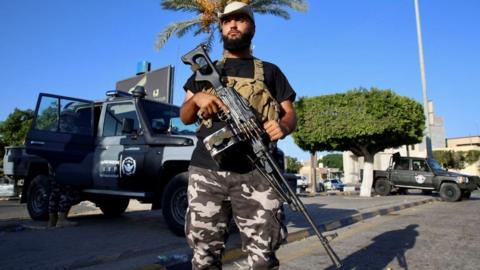 A member of an armed group affiliated with Libya's Ministry of Interior secures a street in Tripoli in August, following clashes that left more than 50 killed and 150 wounded
