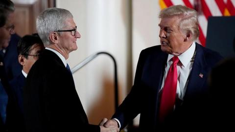 US President Donald Trump wearing a suit and red tie shakes hands with Apple CEO Tim Cook who also wears a dark suit, during a meeting with business leaders at the US Ambassador's Residence on 28 October 2025 in Tokyo, Japan.