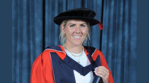 Millie Bright holding a scroll