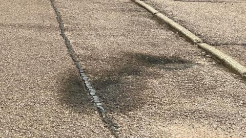 A close-up of black burn marks on a pavement.