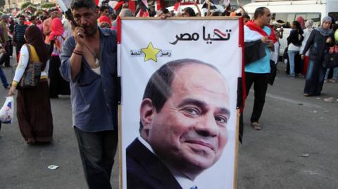 A man holds up a poster of President Abdul Fattah al-Sisi at a rally in Cairo (6 August 2015)