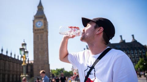 A man drinks a bottle of water on Westminster Bridge
