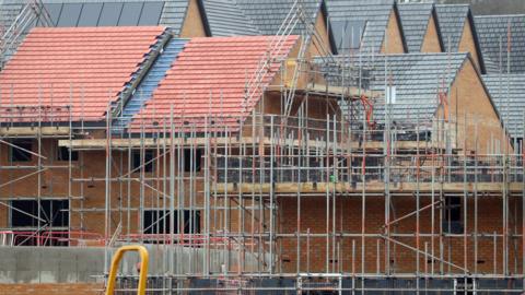 A photo showing houses under construction on a housing development