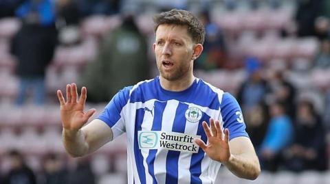 Will Aimson, wearing the blue and white shirt of Wigan, playing last season