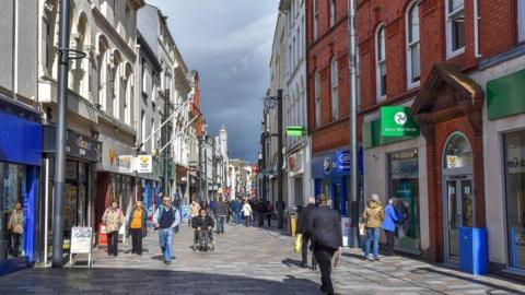 A high street with people walking down it