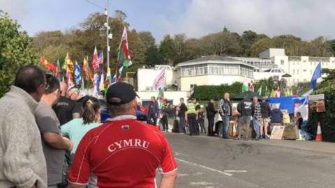 Protesters gather outside the Stradey Park Hotel in Llanelli when plans to use it for temporary housing for asylum seekers was announced.