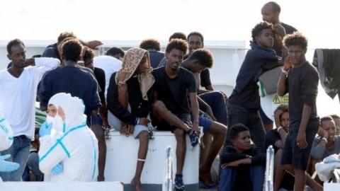 Migrants wait to disembark Italy's coastguard vessel at the port of Catania. Photo: August 2018