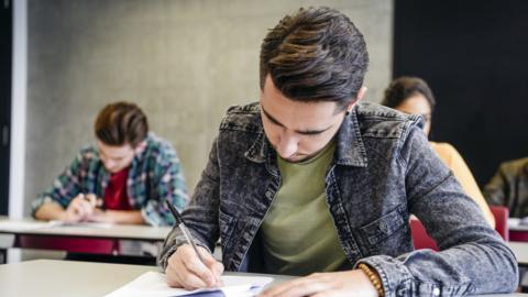 Male college student doing exam - stock photo