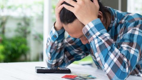 Man looking at credit cards with calculator