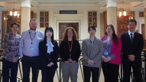 An image of two men and five women standing in front of the entrance to the Council Chamber inside Barnsley town hall.
