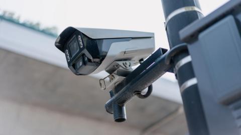 A grey CCTV camera erected on the side of a post.