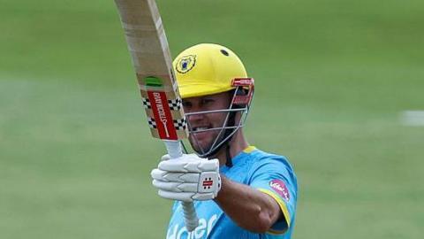 Warwickshire Bears' Beau Webster raising his bat in his left hand.