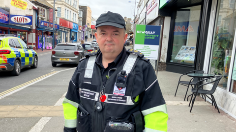 Civil Enforcement officer Andy Hawke is stood on a street in Newquay outside some shops