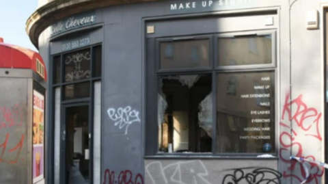 a fire-damaged shop front with smashed windows