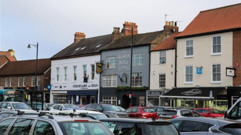 A general view of cars parked on the high street in Yarm, with businesses in the background.