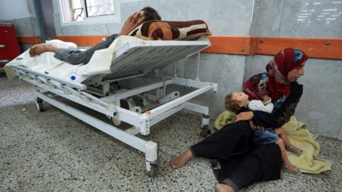 A Palestinian wounded by gunfire near an aid distribution centre in central Gaza, sits on the floor at al-Shifa hospital, in Gaza City (11 June 2025)