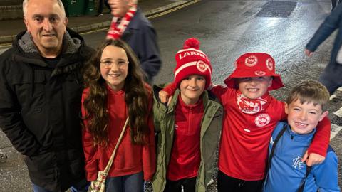 5 Larne fans after the game, outside the stadium wearing red larne tops