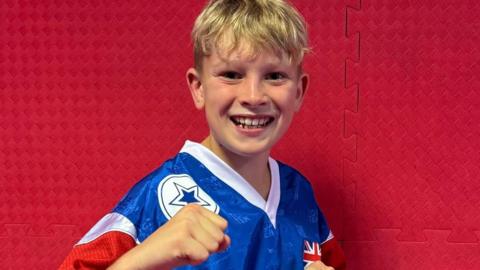 Theo wearing a Team GB top, in a fighting stance, smiling at the camera
