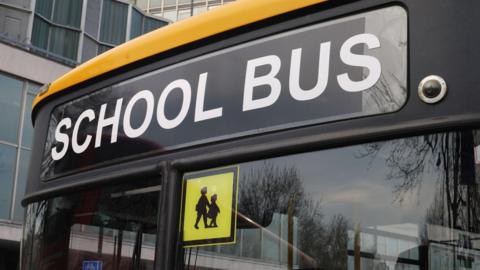 A section of the front of a bus which says 'School bus' in white writing.
