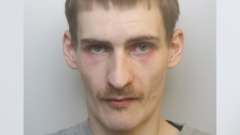 A custody picture of Daniel Gunter, who has dark blonde hair and a blonde moustache. He is looking at the camera with a serious expression and has dark red patches under his eyes.