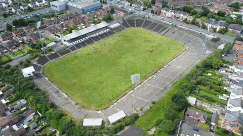 An aerial view of Casement Park, an empty football stadium, with housing developments in the surrounding areas. 