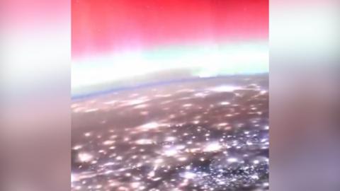 A view of lots of lights on Earth and a glowing pink sky above from the ISS