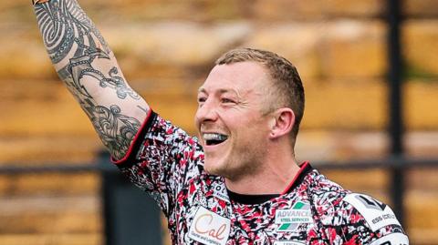 Josh Charnley with his right arm in the air and a big smile on his face after breaking the Super League try-scoring record 