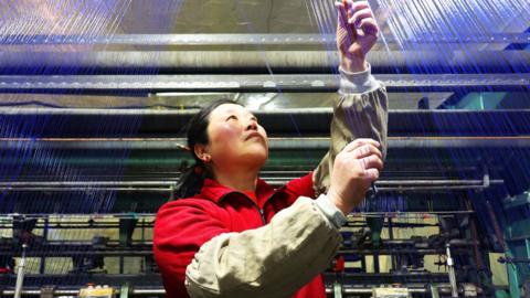 A worker monitors production of yarns at a factory in Suzhou in Eastern China, Januray 2026