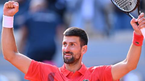 Novak Djokovic raises his arms in celebration after victory over Cameron Norrie at the French Open