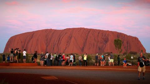 Visitors take photos at Uluru, one Australia's most popular tourist destinations.