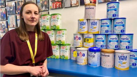 Dee Denton from KidsBank in Chester next to tins of infant milk formula