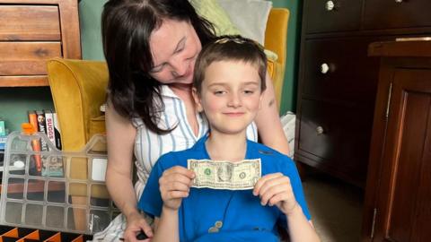 Tommy Dawson cross-legged, in front of his mother Helen, surrounded by the coin collection