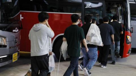 Repatriated South Korean workers detained in a US Immigration and Customs Enforcement raid at a Georgia factory queue to board buses at Incheon International Airport in Incheon, South Korea, 12 September 2025.