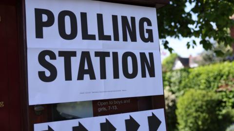 A large sign with the words polling station in black on a white background