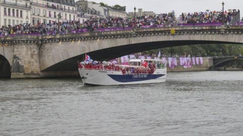 Athletes sail in a boat along the River Seine as rain starts at the beginning of the opening ceremony of the Paris 2024 Olympic Games