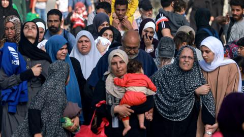 Palestinians fleeing Gaza City and other parts of northern Gaza towards the southern areas, walk on a road on 8 November 2023