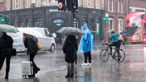 people standing in a street with heavy rain holding umbrellas