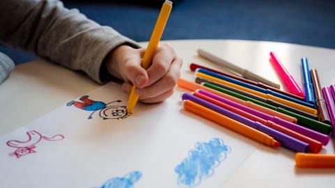 a child drawing a picture with their left hand