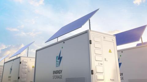 A row of battery storage units with solar panels on top, they are white and read 'Energy Storage'