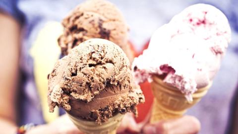 Hands holding ice cream cones with different flavour ice creams