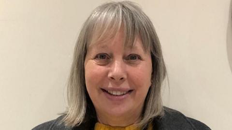 Carol Hyatt smiling. She has grey hair that is styled into a bob with a fringe