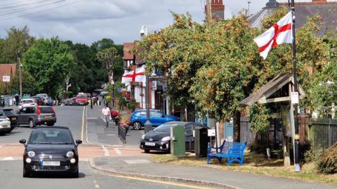 Barnt Green High Street, with England flags hung from the poles on the side of the road.