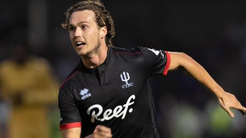 Harry Forster running in black Crawley Town away kit with his left arm out