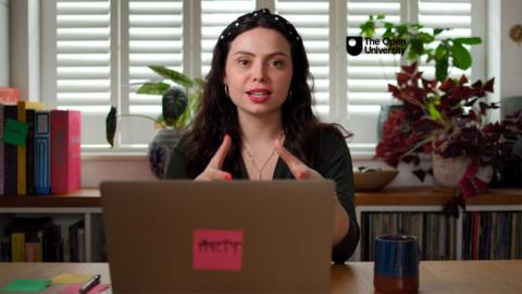 Author Sophia Smith Galer sitting at a desk with her laptop open, looking into the camera.